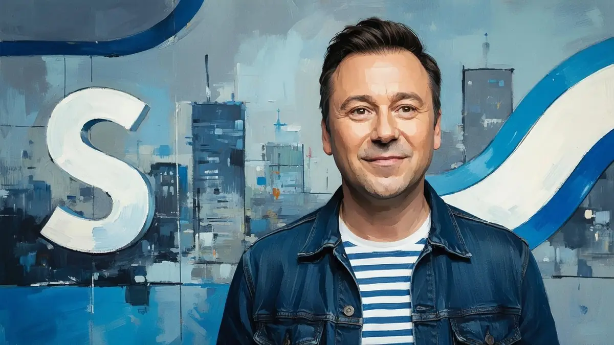 Portrait souriant de l'acteur Andy Cocq portant une veste en jean sur un t-shirt rayé devant un fond peint