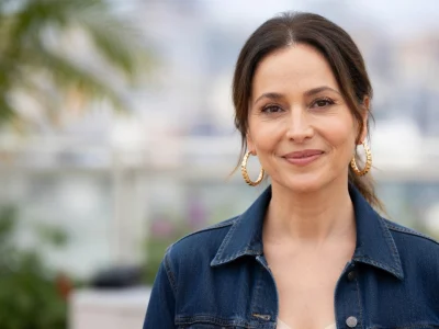 Anne Charrier arbore un léger sourire vêtue d'une veste en jean et de boucles d'oreilles dorées.