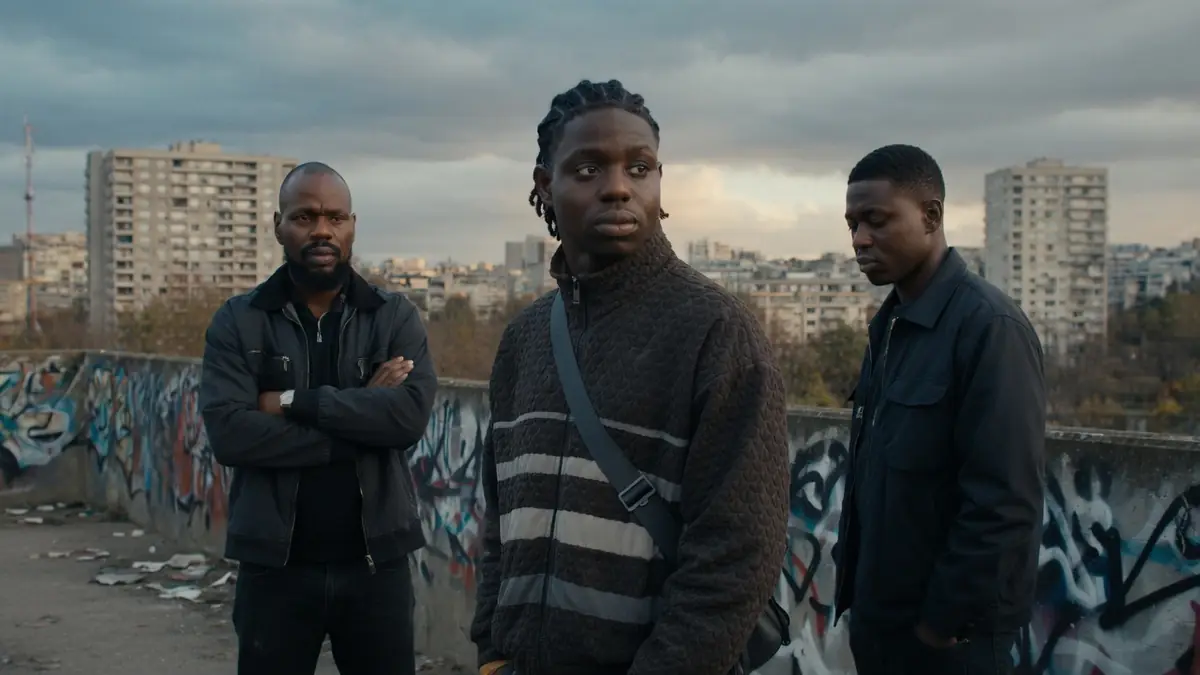 Trois jeunes hommes se tiennent sur un toit urbain dans une scène du film Banlieusards 3