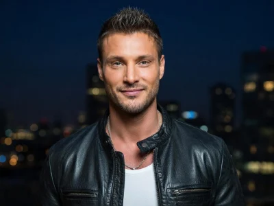 Benjamin Bove sourit en veste en cuir devant un fond urbain illuminé la nuit