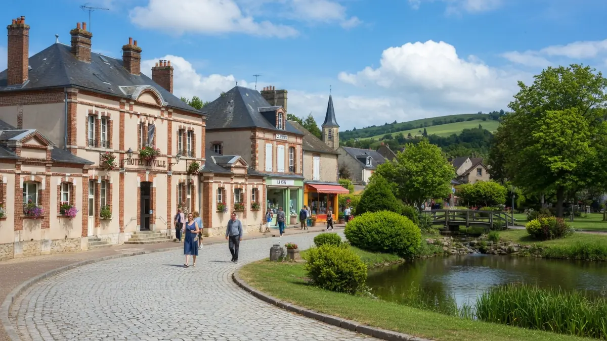 Vue pittoresque à Bléneau d'une rue pavée bordée de maisons anciennes et d'un étang
