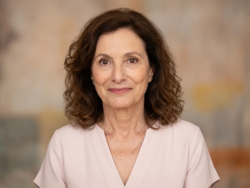 Brigitte Roüan arbore un léger sourire dans ce portrait en haut rose pâle.