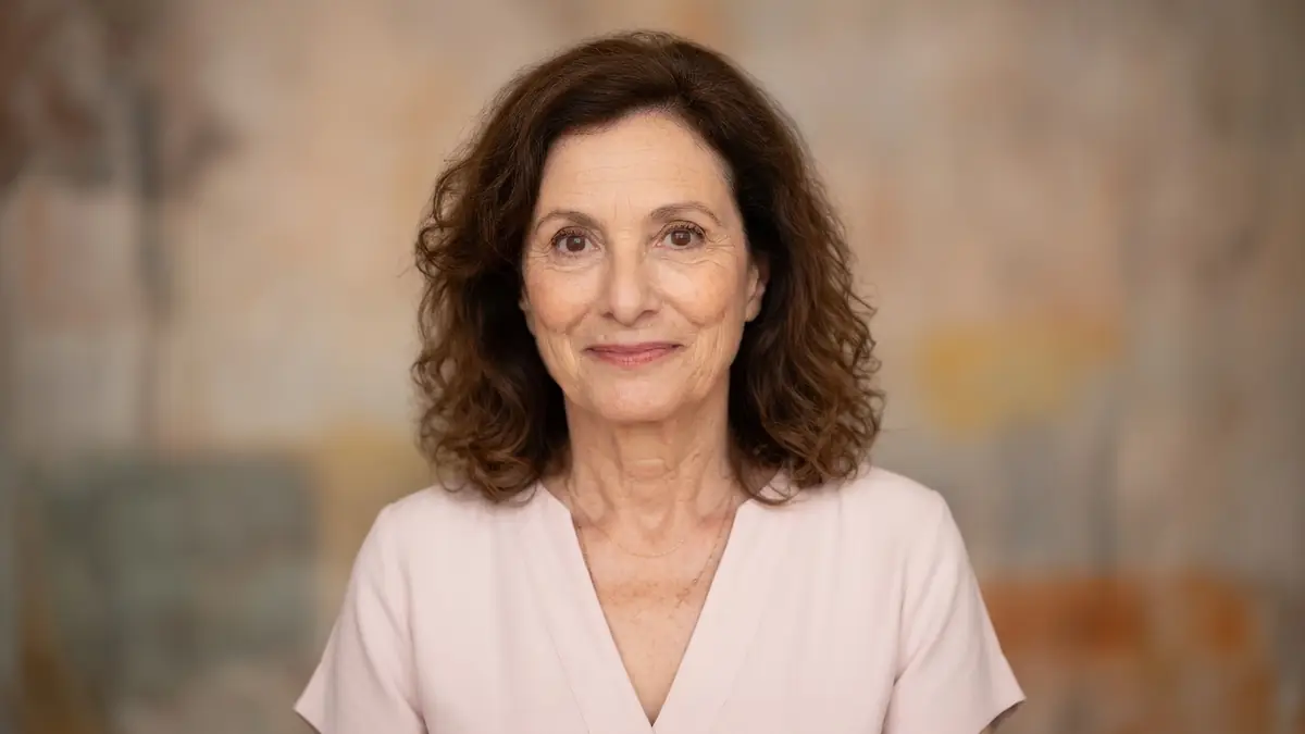 Brigitte Roüan arbore un léger sourire dans ce portrait en haut rose pâle.