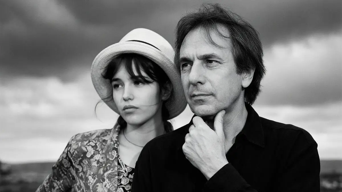 Bruno Nuytten et une jeune femme au chapeau dans un portrait en noir et blanc