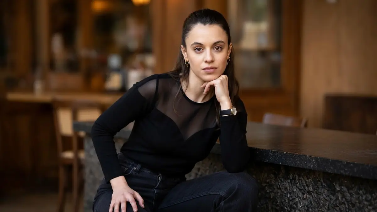 Portrait de la comédienne Camille Genau posant avec élégance dans un décor intérieur sombre