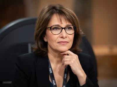 Carole Rousseau pose avec sa main sur le menton dans un studio de télévision