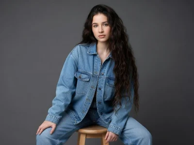 Catherine Davydzenka pose assise sur un tabouret en tenue denim bleue