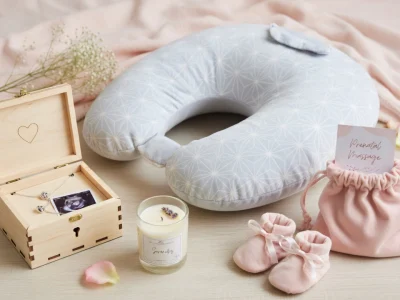 Un coussin d'allaitement avec bougie et chaussons compose un cadeau pour une future maman