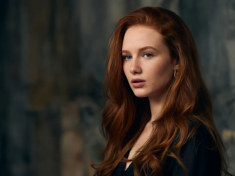 Portrait d'une jeune femme rousse au regard intense, l'actrice clémence boeuf pose devant un fond sombre