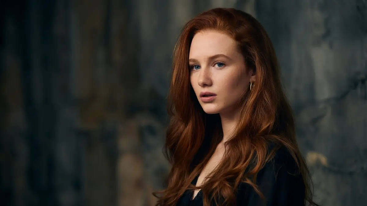 Portrait d'une jeune femme rousse au regard intense, l'actrice clémence boeuf pose devant un fond sombre