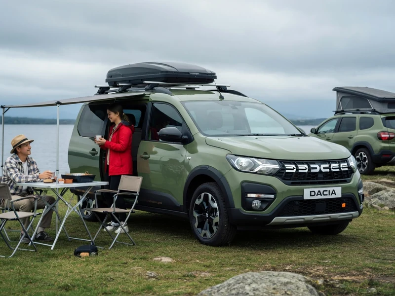Un couple prend son repas près d'une Dacia camping-car au bord d'un lac