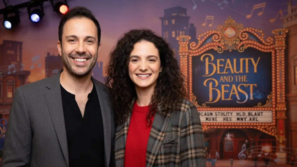 Dan Menasche pose souriant aux côtés d'une femme devant un décor de théâtre