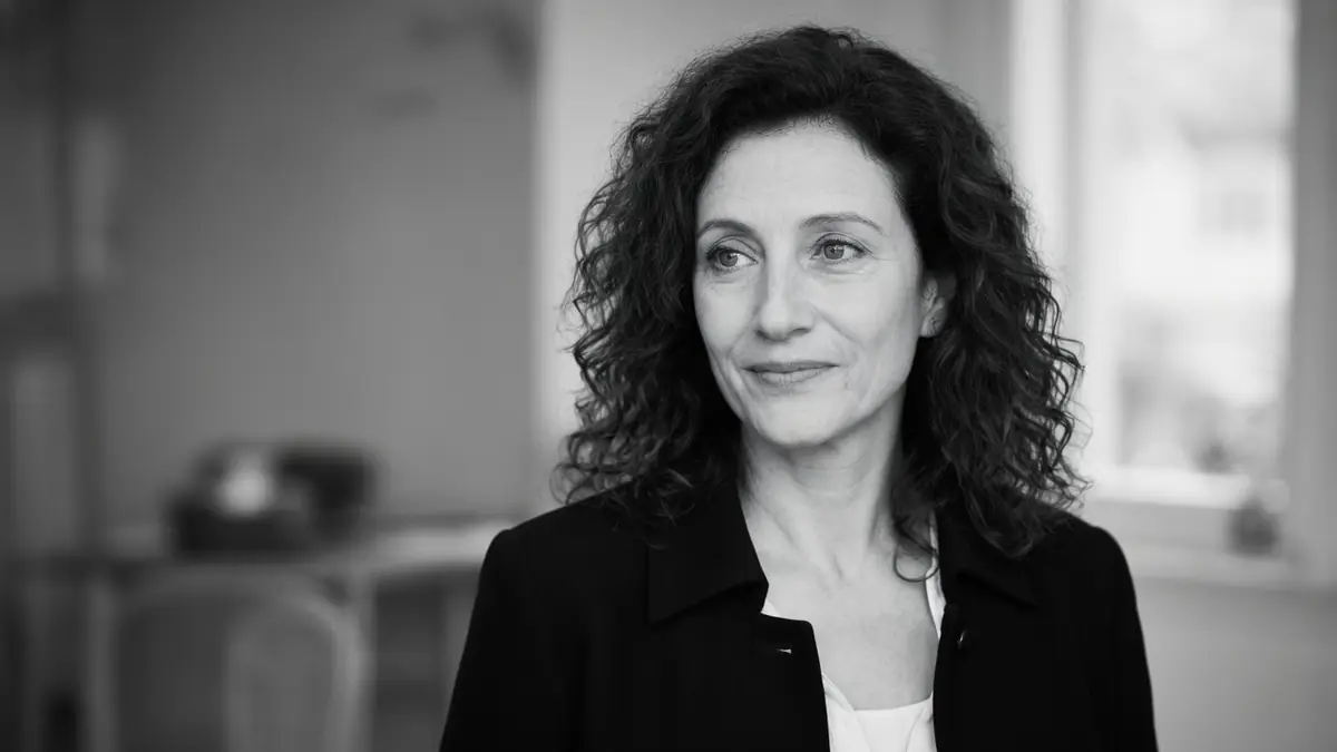 L'image en noir et blanc montre Danièle Arditi aux cheveux bouclés et veste sombre