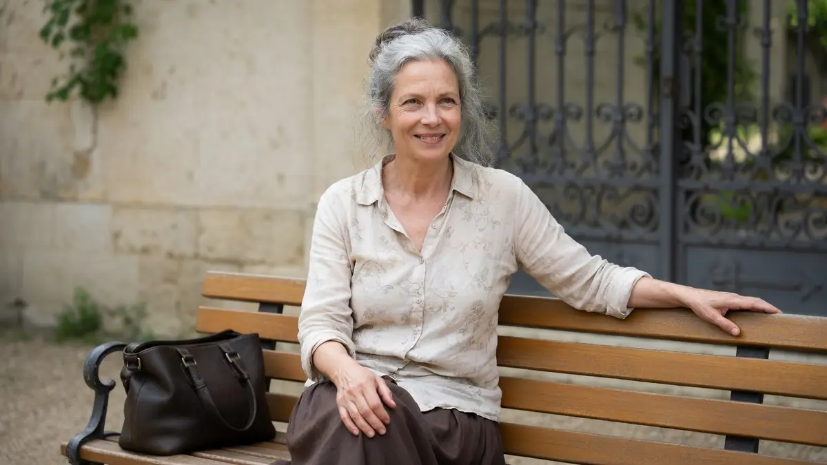 Clémentine Amouroux est assise sur un banc en bois avec un sac à ses côtés