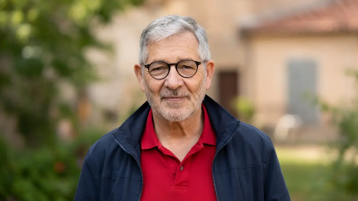 Yves Pignot pose en polo rouge et veste bleue devant un décor extérieur