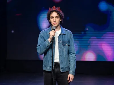 Léo Rispal se tient sur scène avec un micro à la main et une couronne sur la tête