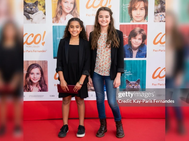 Lola Lasseron pose aux côtés d'une autre jeune fille sur le tapis rouge
