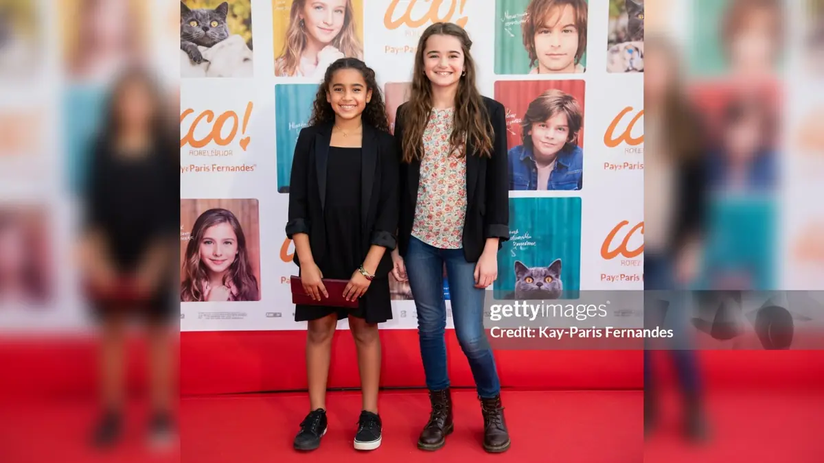 Lola Lasseron pose aux côtés d'une autre jeune fille sur le tapis rouge