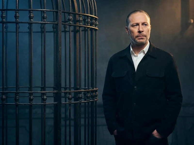Martial Bezot se tient près d'une grande cage métallique dans un décor sombre