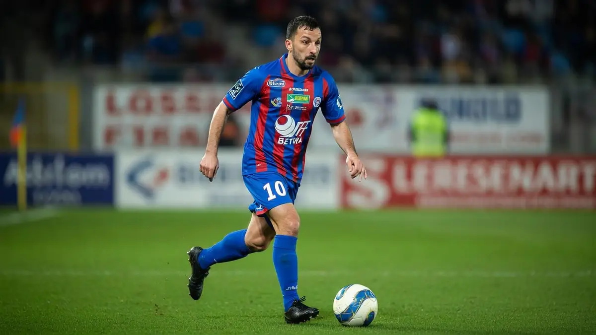 Christophe Aubanel conduit le ballon sur le terrain de football.