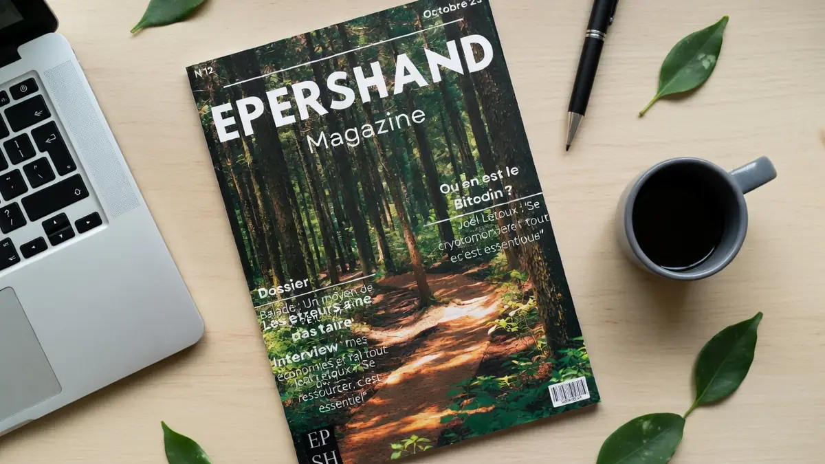 Epershand Magazine repose sur une table en bois à côté d'un ordinateur portable et d'une tasse de café