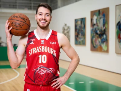 Hugo Invernizzi pose avec un ballon de basket dans une salle de sport