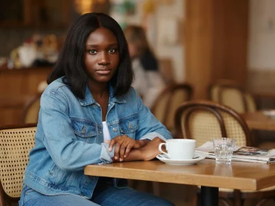 Jeaneta Domingos assise à la table d'un café, une tasse à la main, dans une ambiance décontractée