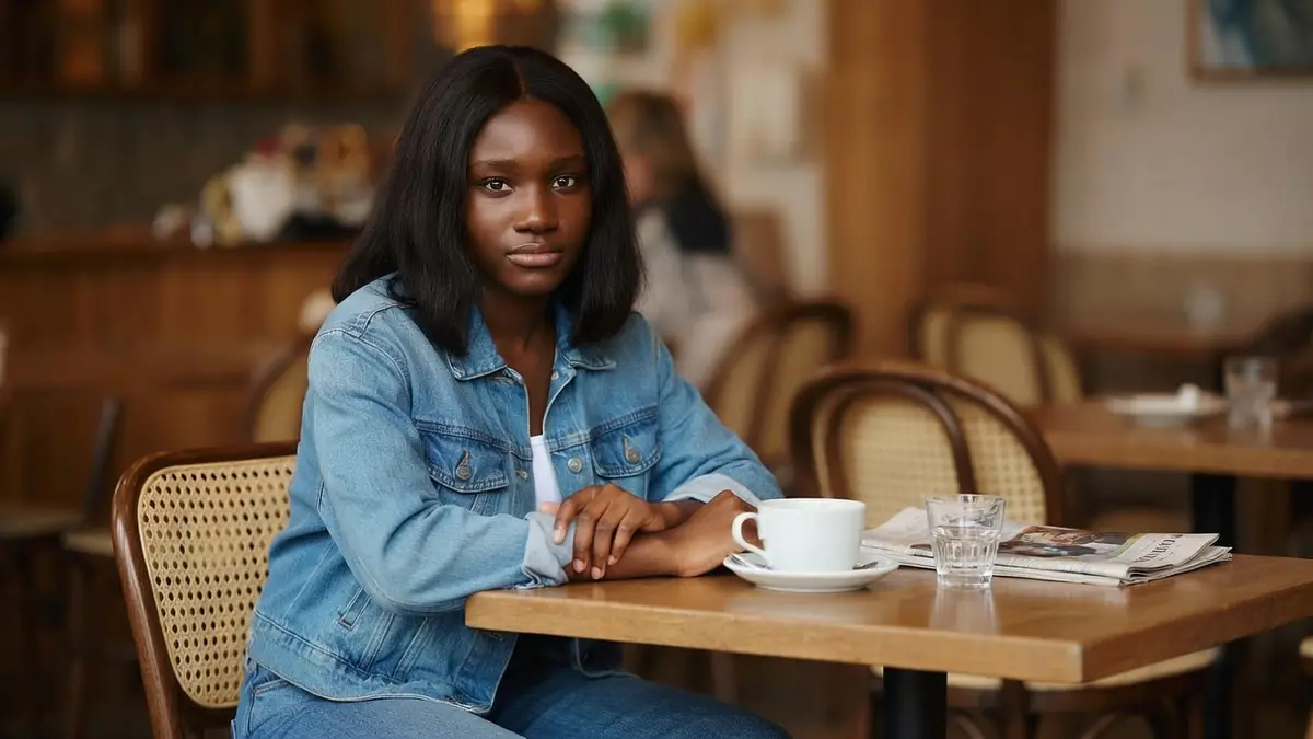Jeaneta Domingos assise à la table d'un café, une tasse à la main, dans une ambiance décontractée