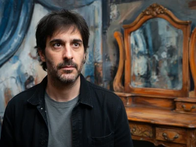 Julien Honoré se tient devant un miroir dans un décor artistique peint en bleu.