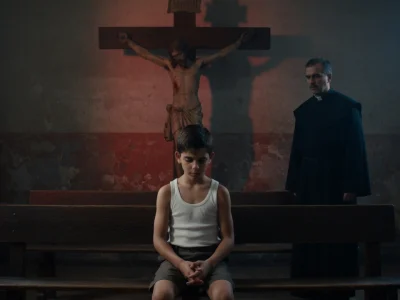 Un jeune garçon assis dans une église sombre illustre une scène marquante de La Mauvaise Éducation