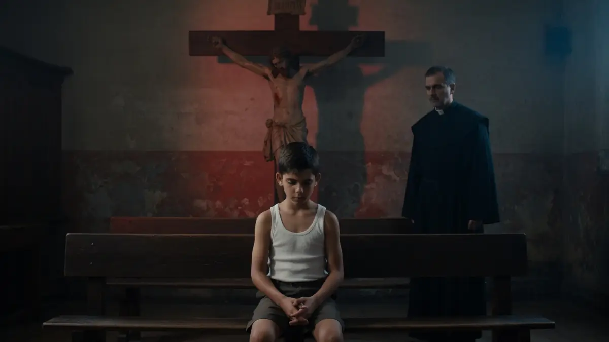Un jeune garçon assis dans une église sombre illustre une scène marquante de La Mauvaise Éducation