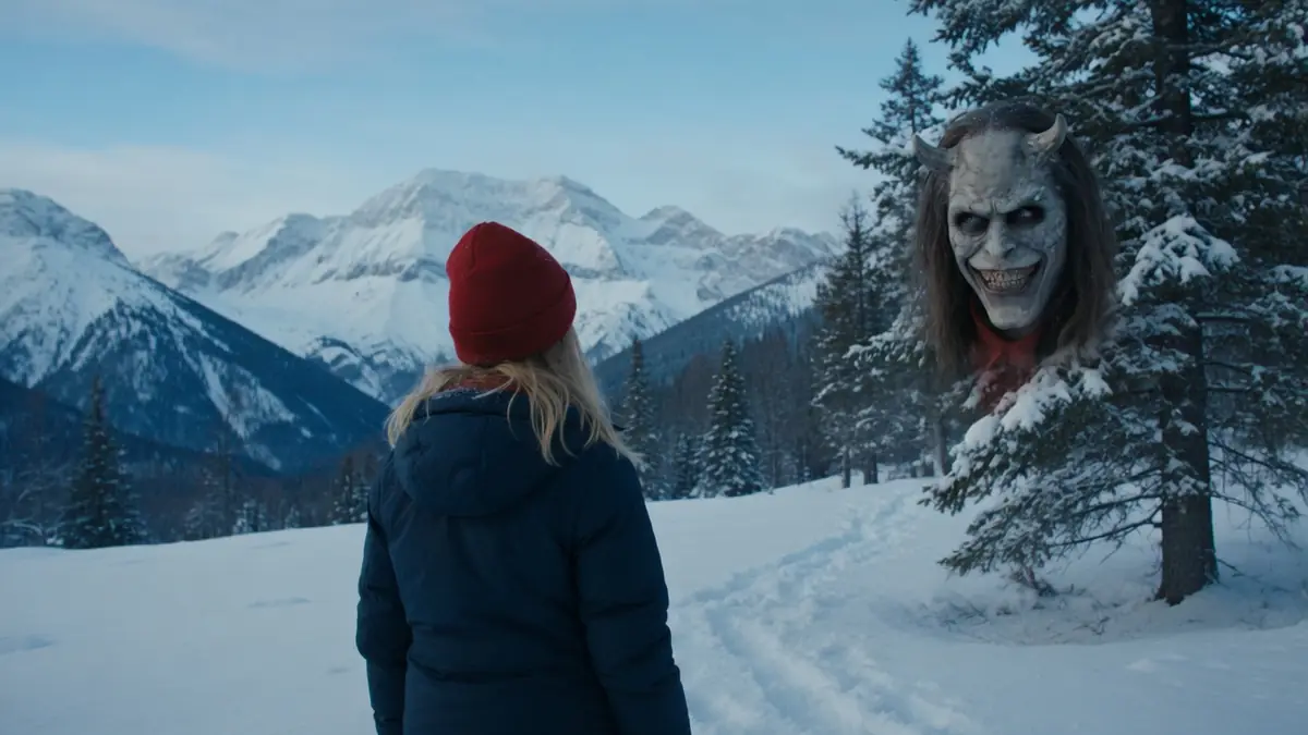 Une jeune femme en bonnet rouge face à une entité masquée effrayante dans un paysage enneigé pour Black Phone 2