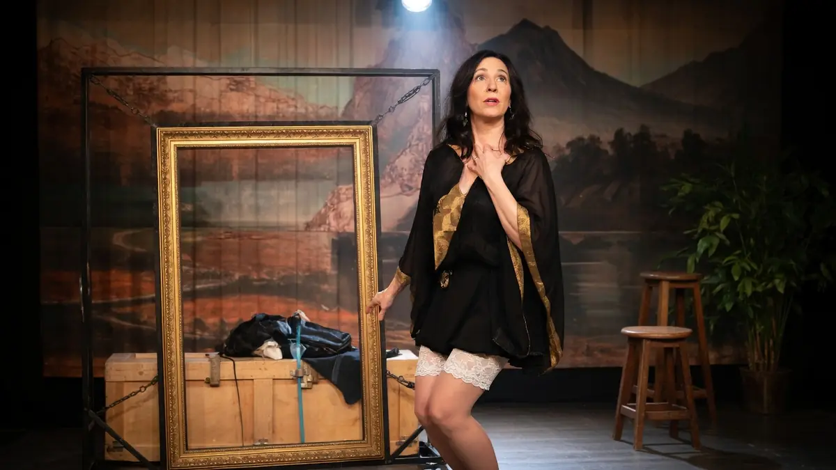 Karina Marimon se tient sur scène la main sur la poitrine dans un décor théâtral