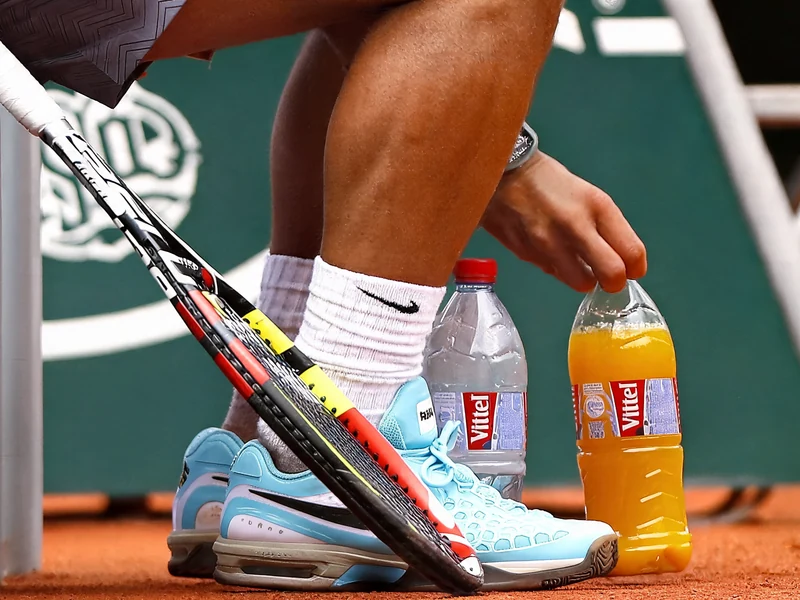 Un joueur de tennis assis avec sa raquette et sa boisson pour le tennis sur le court