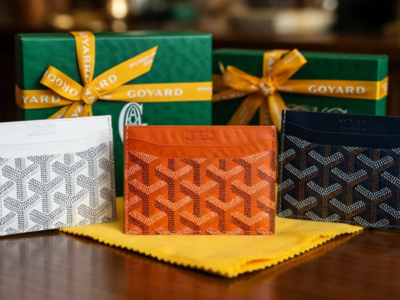 Plusieurs Goyard porte-carte colorés sont posés sur un tissu jaune devant des boîtes vertes