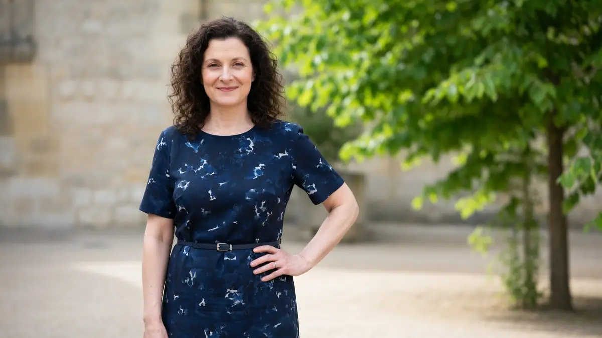 Portrait de serpentine Teyssier en robe bleue à motifs devant un mur de pierre