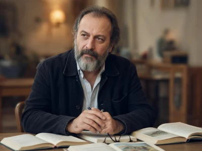 Patrick Pineau est assis à une table avec des livres ouverts devant lui