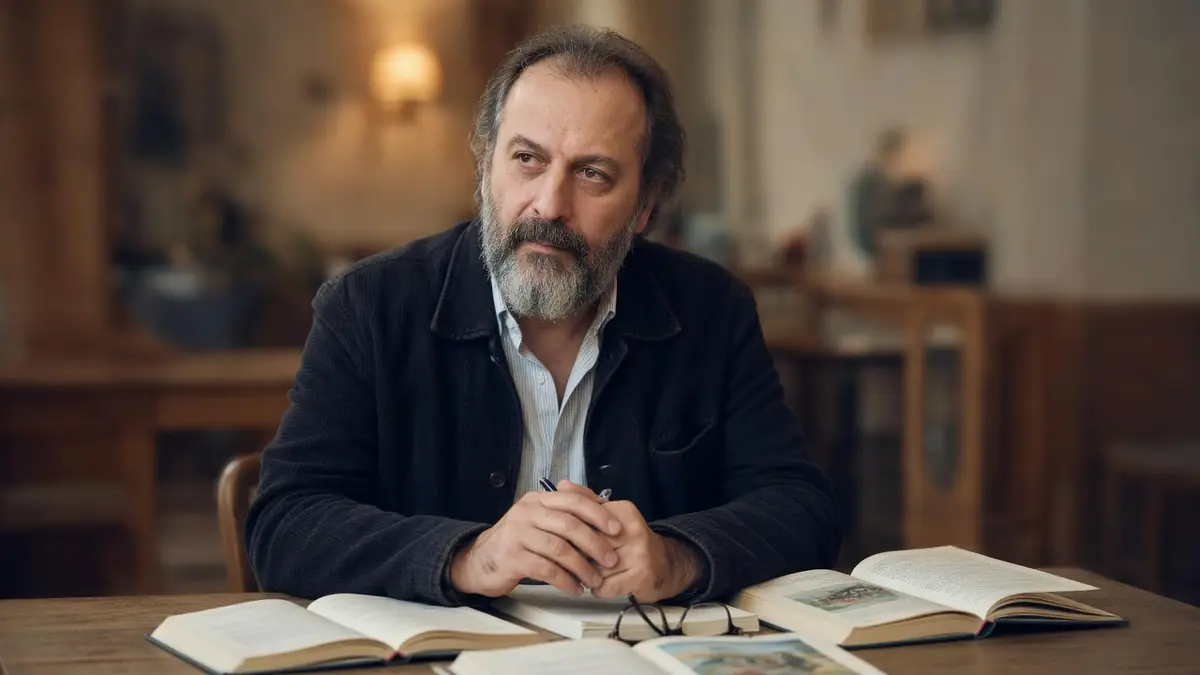 Patrick Pineau est assis à une table avec des livres ouverts devant lui