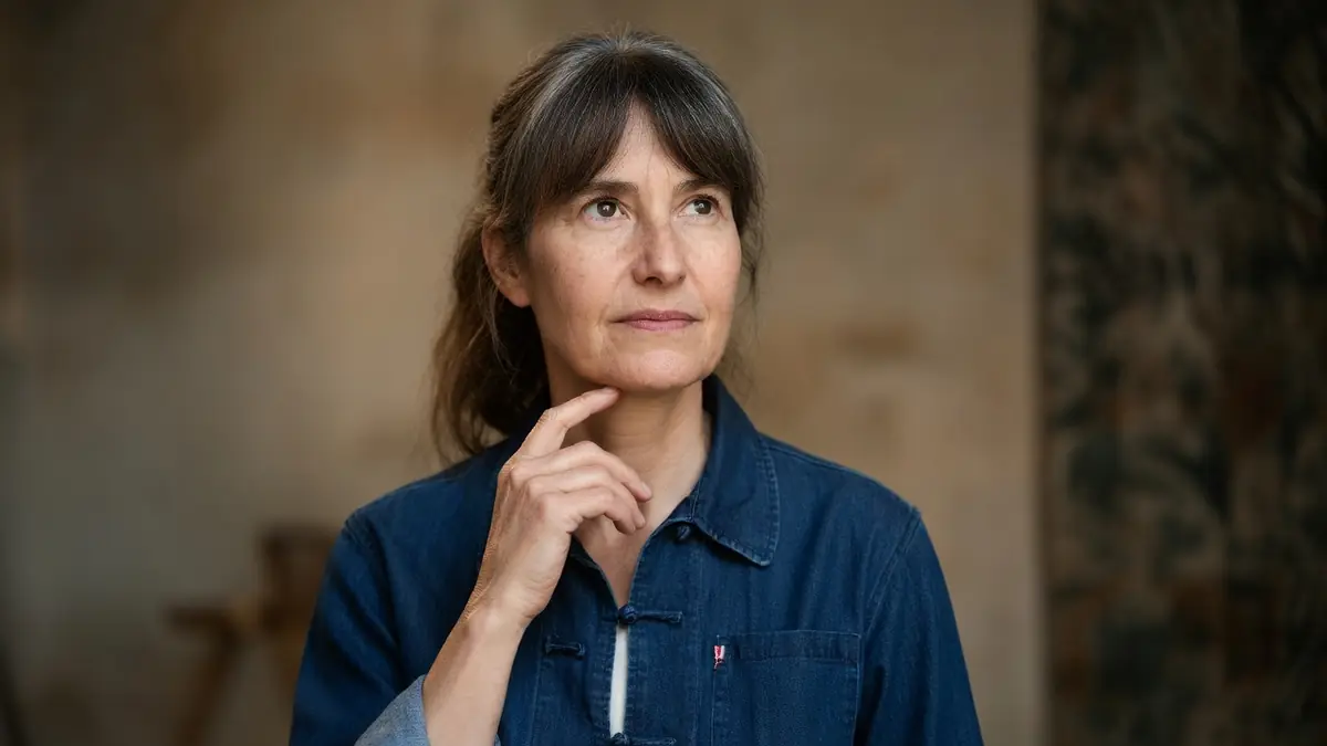Portrait de la cinéaste Laetitia Masson portant une chemise en jean et regardant au loin avec une expression pensive