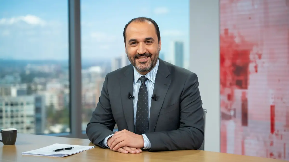 Messaoud Benterki sourit les mains croisées sur un bureau dans un studio avec vue sur la ville