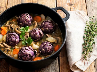 Une cocotte d'un artichaut à la barigoule mijoté avec carottes et champignons