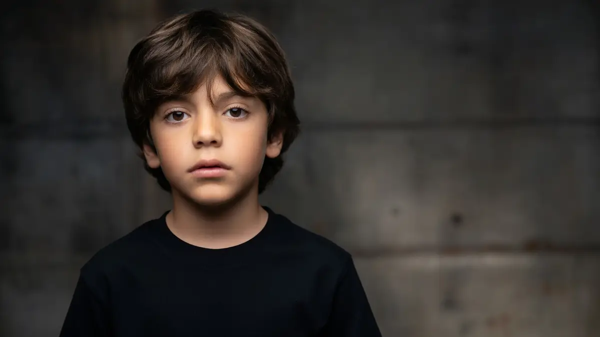 Portrait de l'acteur Noé chabbat posant avec un regard sérieux sur un fond sombre
