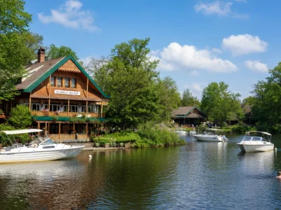 Le chalet des Îles se dresse au bord d'un lac avec des bateaux amarrés et des arbres verts