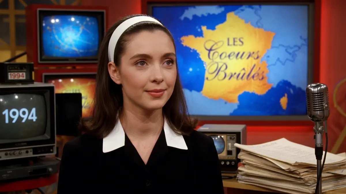 Amélie Pick dans un studio de télévision vintage avec des téléviseurs et un micro