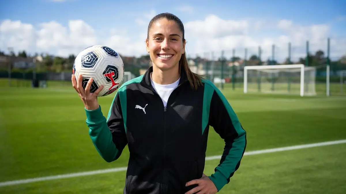 Inès Benyahia sourit en tenant un ballon sur un terrain de football