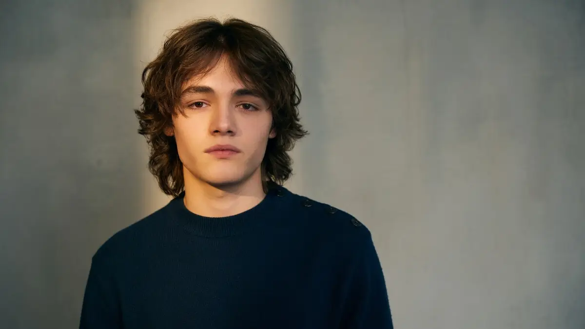 Alexis Rosenstiehl pose en pull bleu marine devant un fond gris