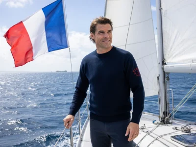 Jean Galfione debout sur un voilier en mer avec le drapeau français qui flotte