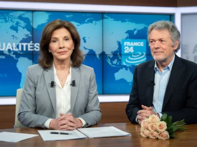 Béatrice Schönberg est assise à côté d'un homme derrière un bureau dans un studio de télévision