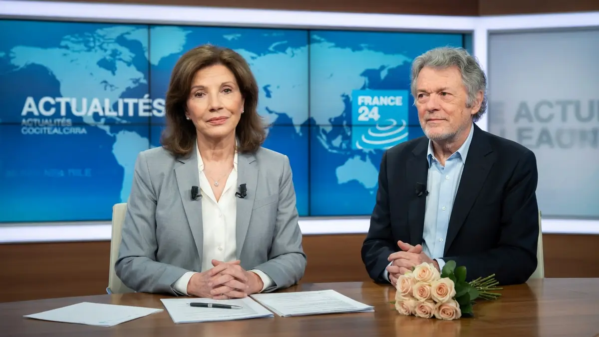 Béatrice Schönberg est assise à côté d'un homme derrière un bureau dans un studio de télévision