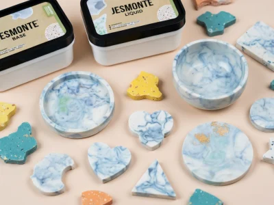 Divers objets artisanaux colorés et marbrés fabriqués en Jesmonite sur fond neutre